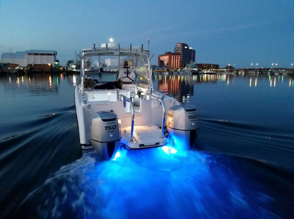 Boat at dusk with blue SeaBlaze X2 underwater lighting against a city skyline